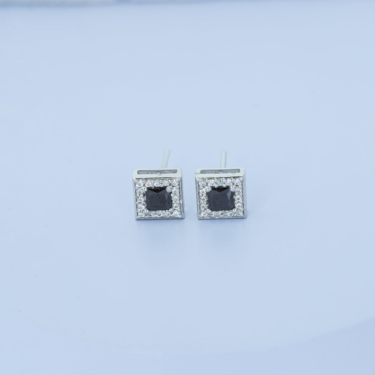 Black princess halo square stud earrings with white pave border and tilted diamond frame
