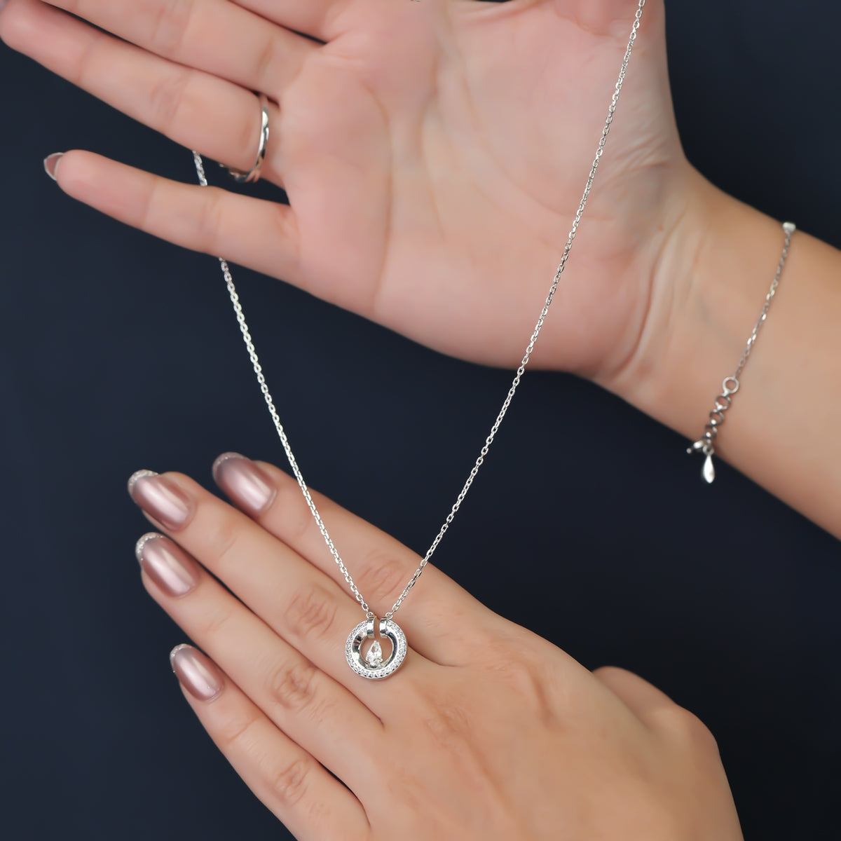 Silver chain necklace with a paved circle pendant enclosing a crystal drop
