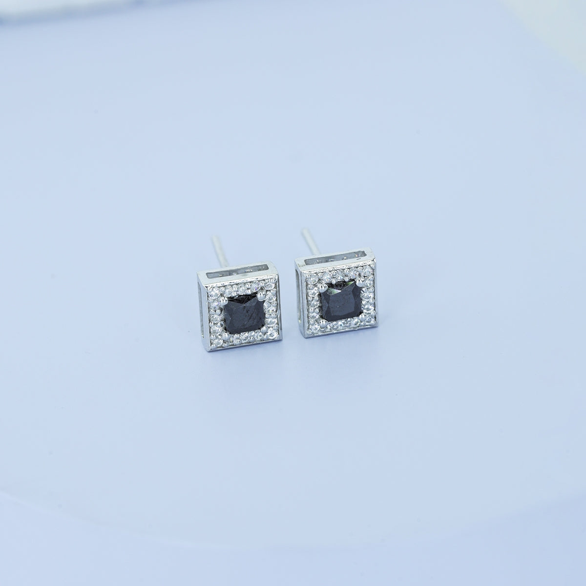 Black princess halo square stud earrings with white pave border and tilted diamond frame