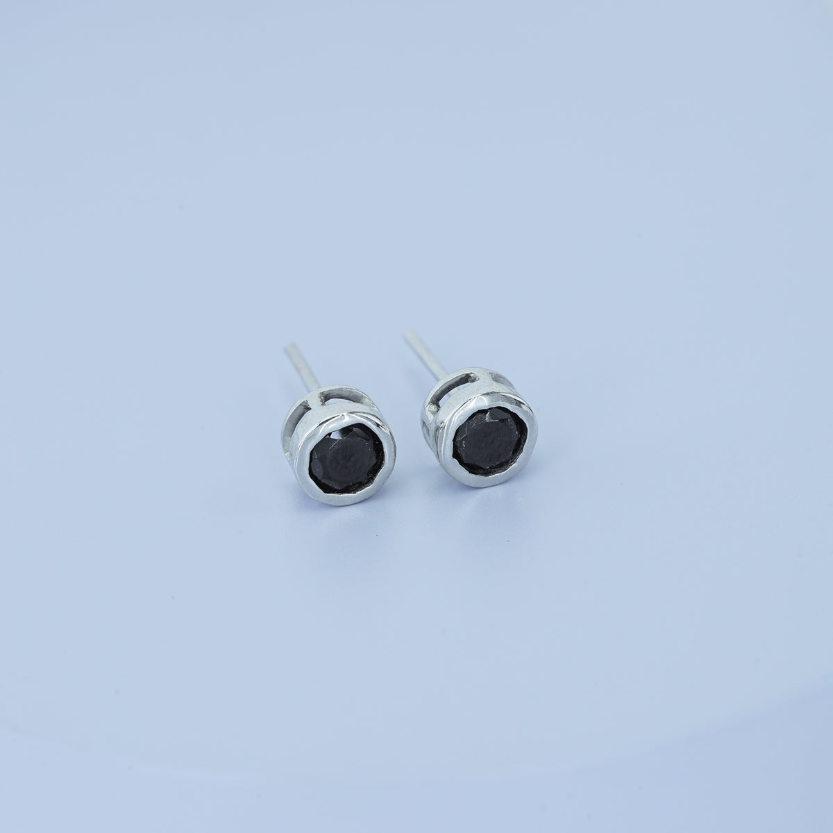 Black round stud earrings with polished circular bezel frame