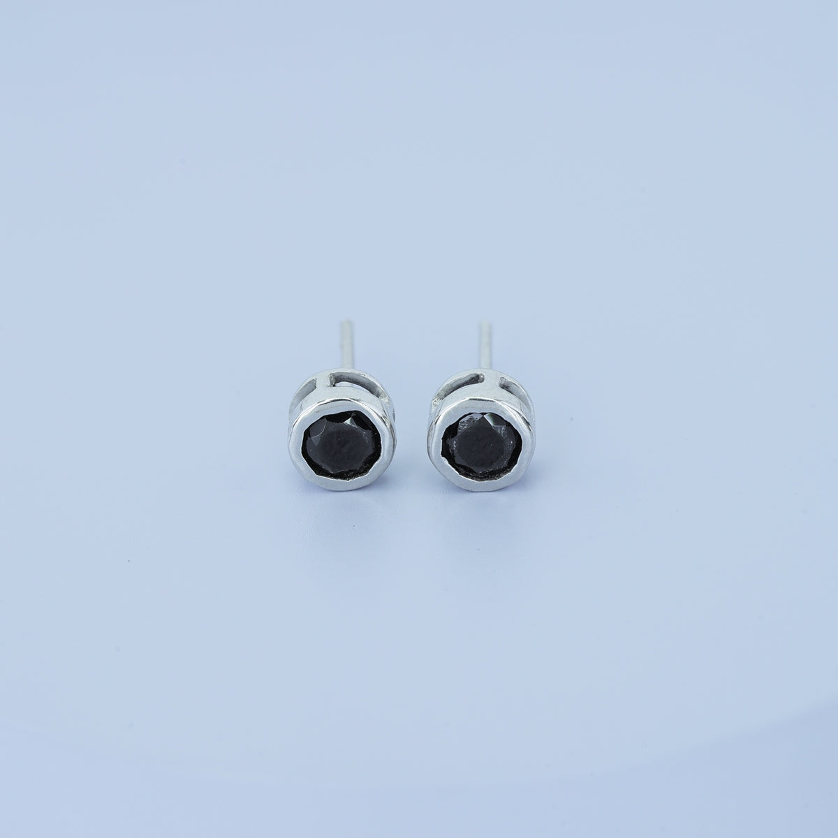 Black round stud earrings with polished circular bezel frame