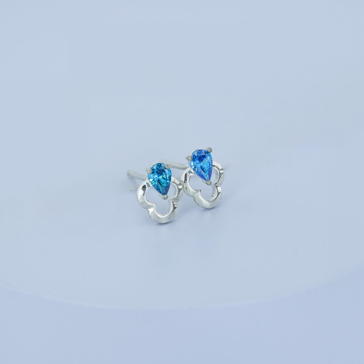 Blue pear drop floral stud earrings with open quatrefoil base and raised stone top