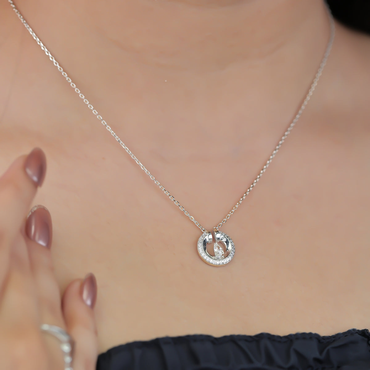 Silver chain necklace with a paved circle pendant enclosing a crystal drop