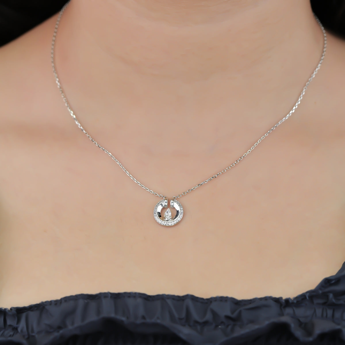 Silver chain necklace with a paved circle pendant enclosing a crystal drop