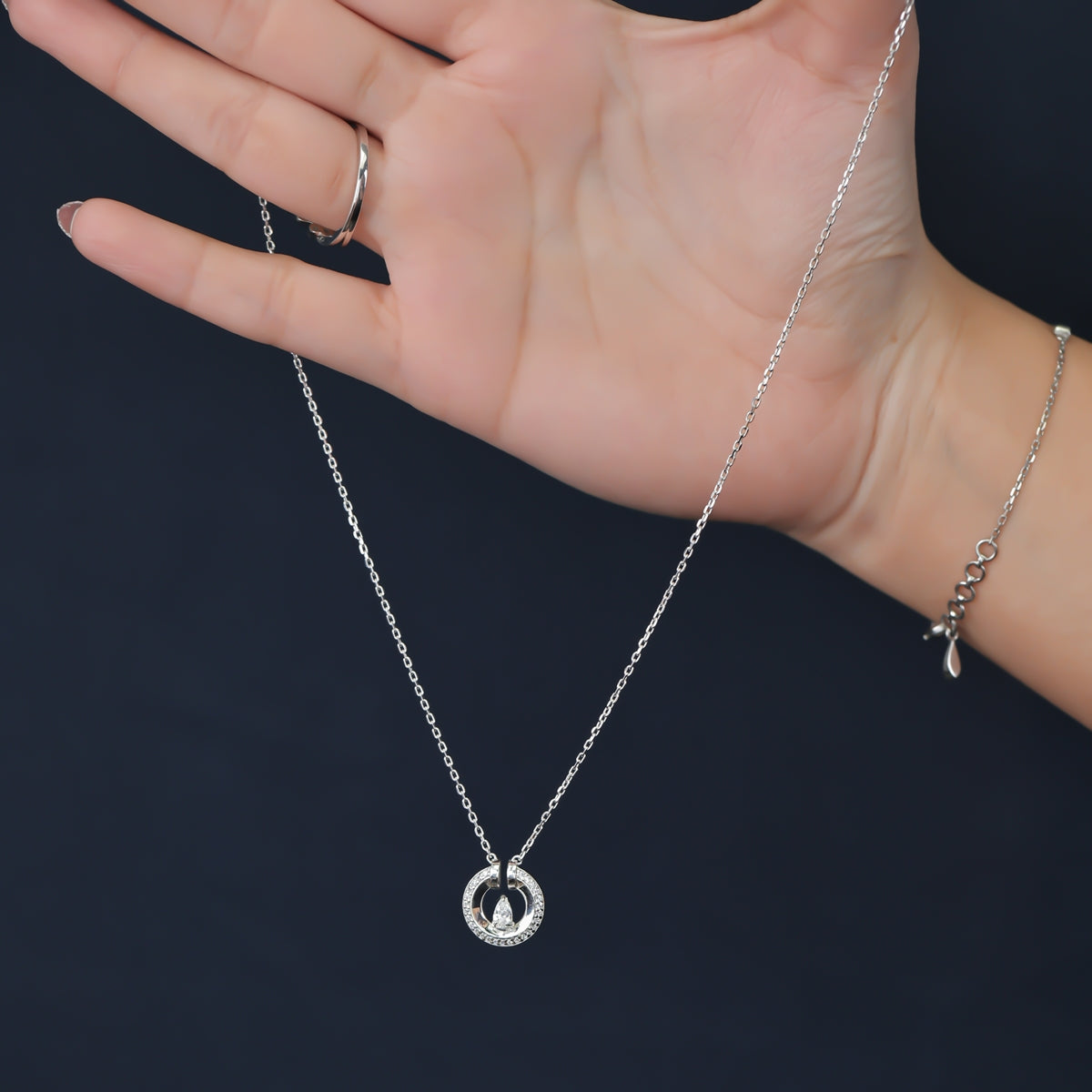 Silver chain necklace with a paved circle pendant enclosing a crystal drop
