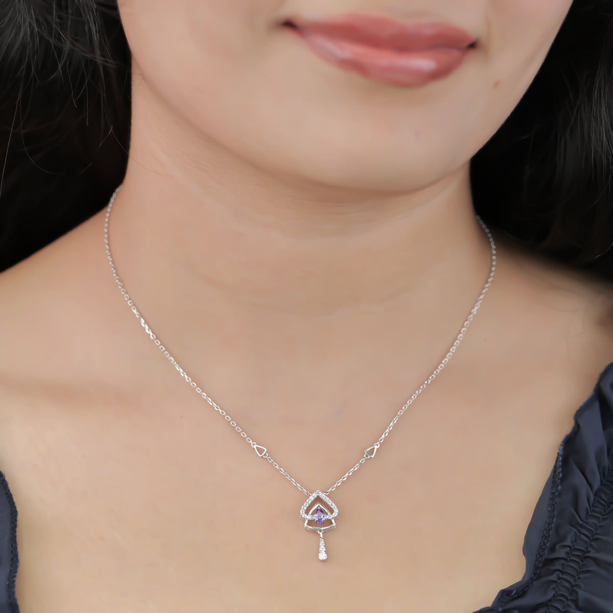 Silver chain necklace with a layered triangular pendant and purple gem