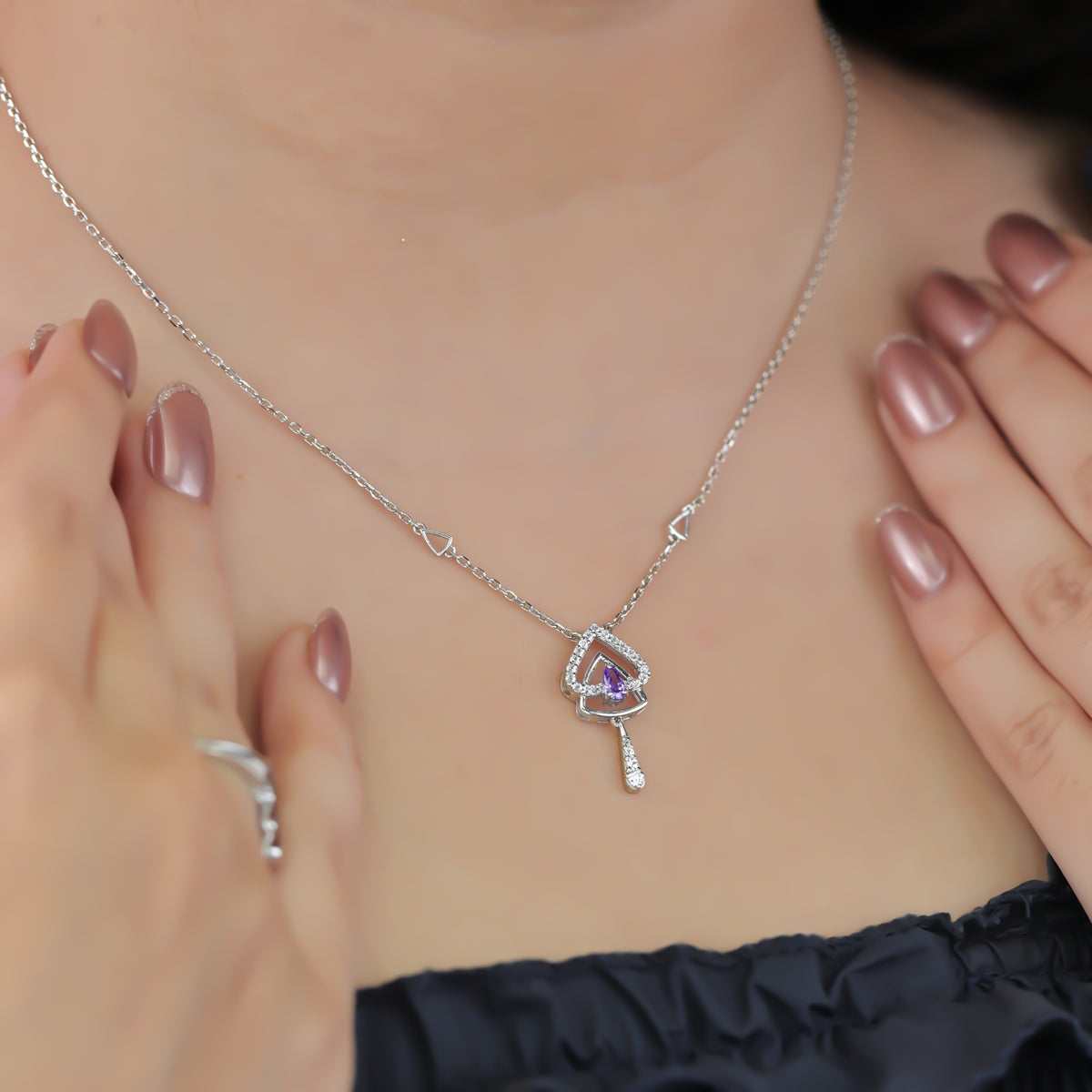 Silver chain necklace with a layered triangular pendant and purple gem