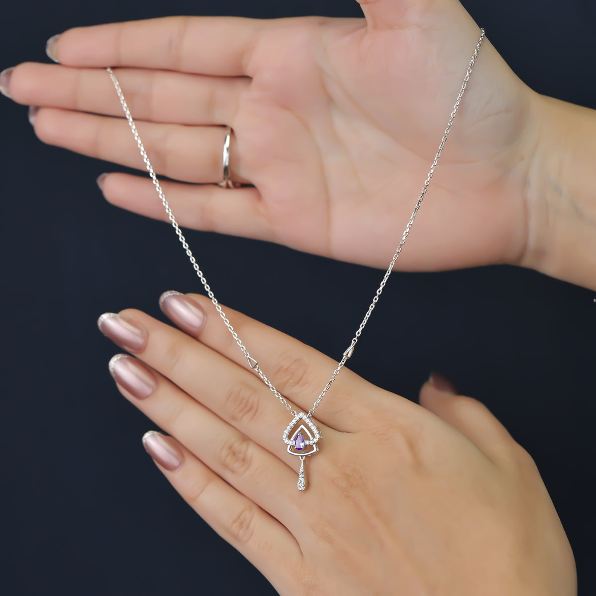 Silver chain necklace with a layered triangular pendant and purple gem