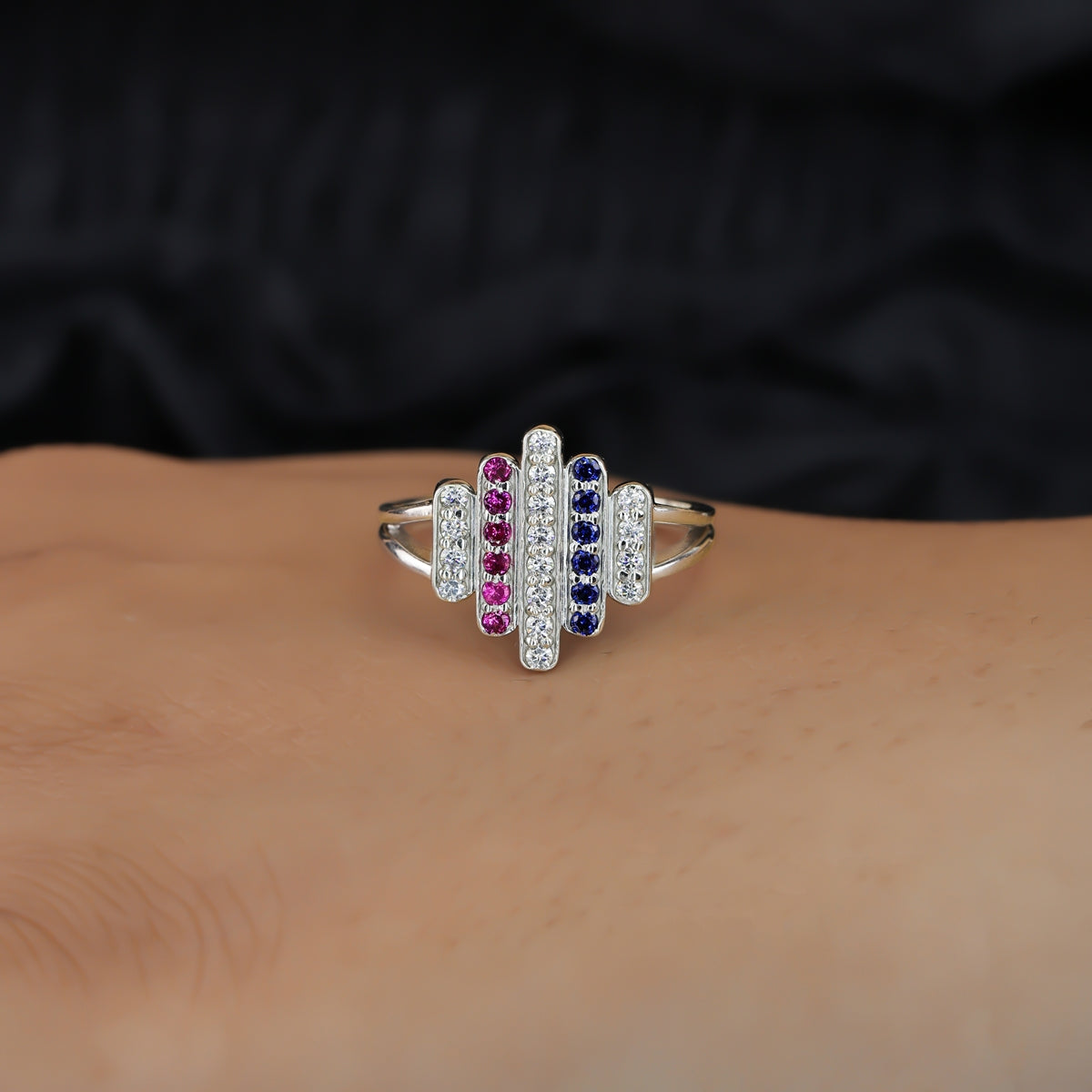 Statement ring featuring vertical rows of clear, pink, and dark blue stones