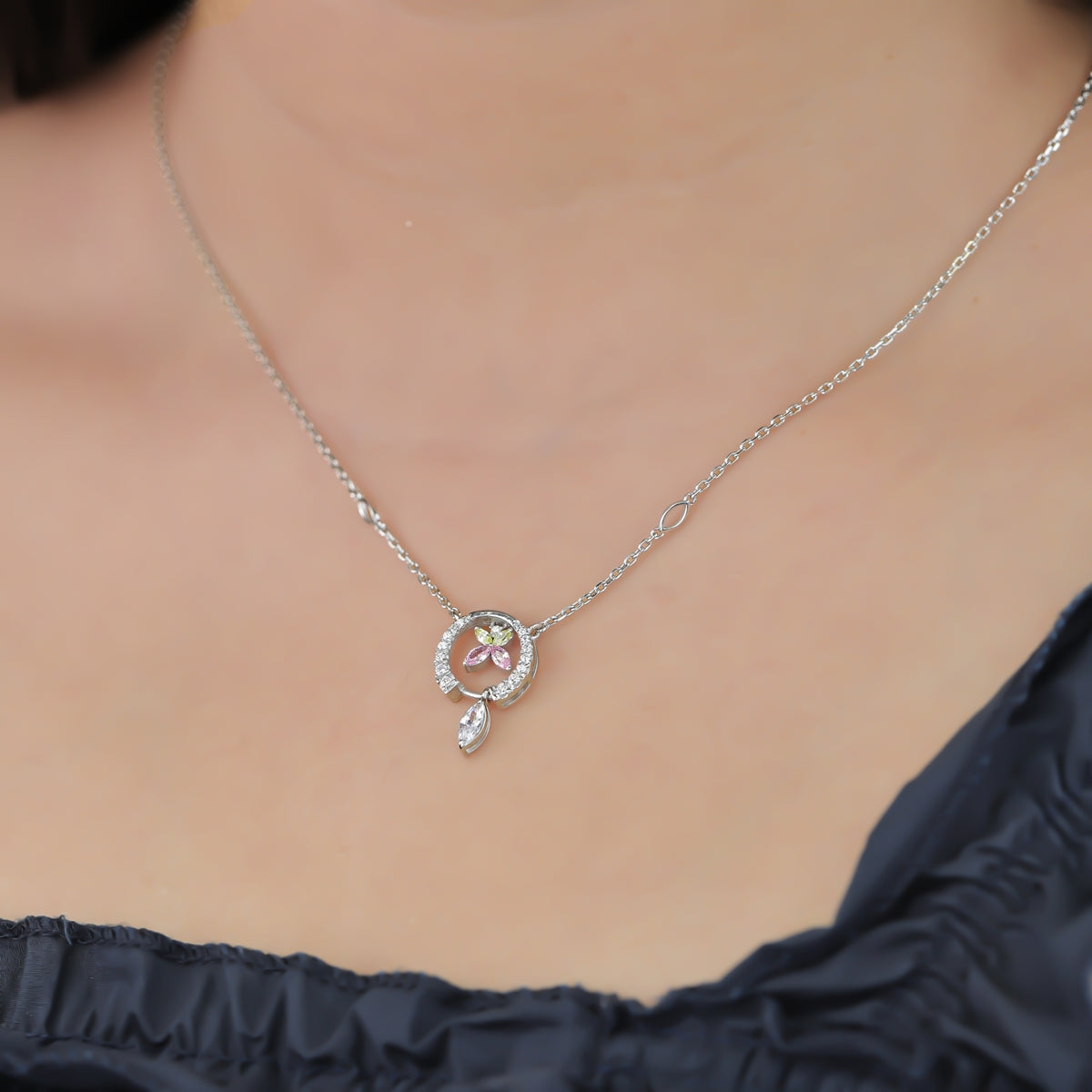 Paved circle pendant enclosing a colorful butterfly with a hanging crystal