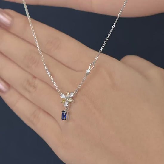 Silver necklace with a yellow floral pendant and blue gem