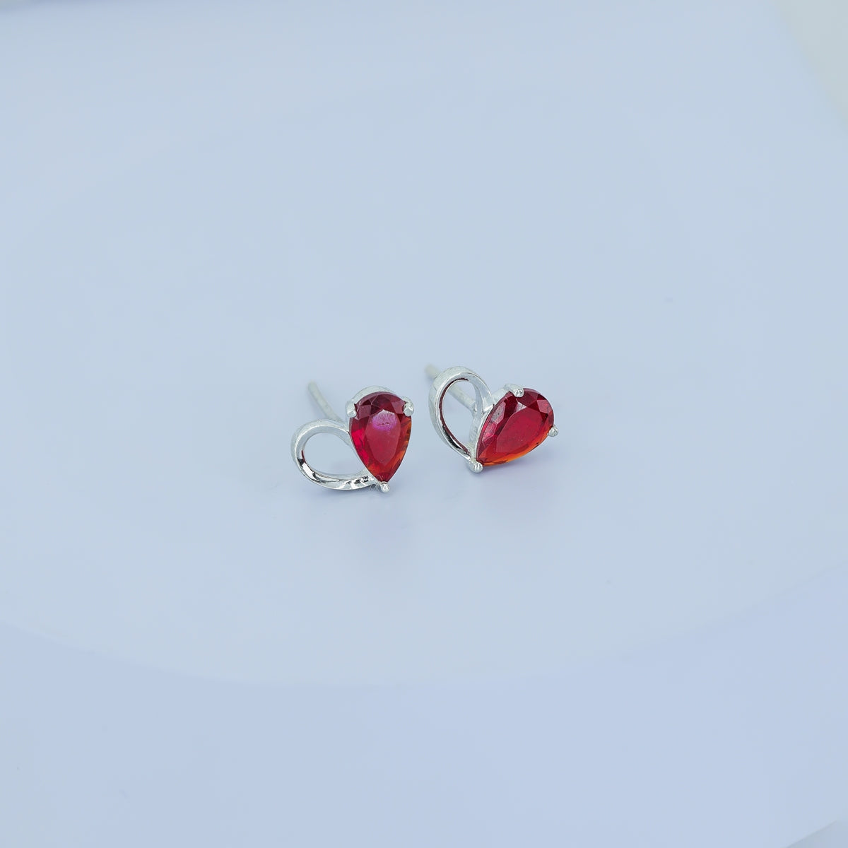 Ruby red heart loop stud earrings with open teardrop swirl base and pear stone top