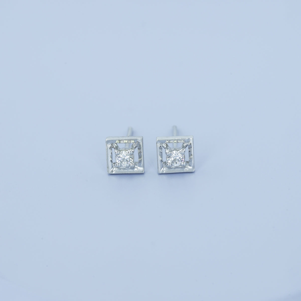 Square claw stud earrings with tilted open frame and raised round centre