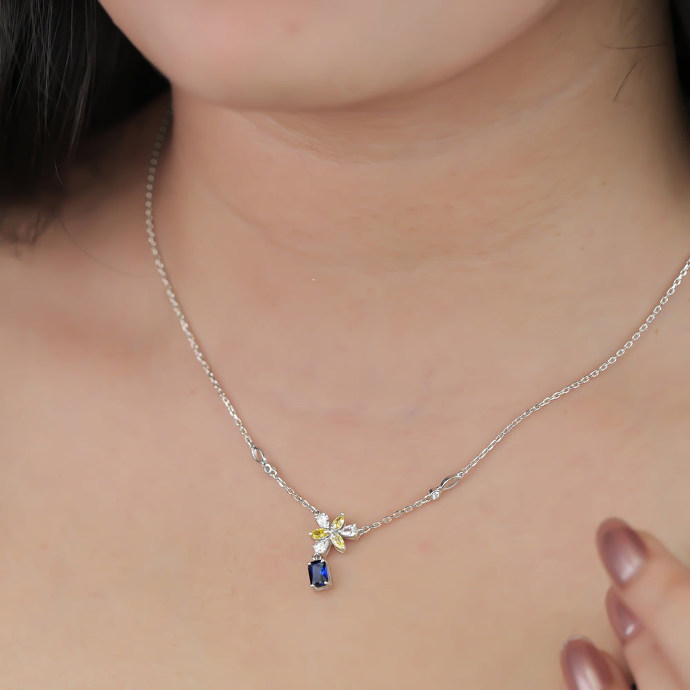 Silver necklace with a yellow floral pendant and blue gem
