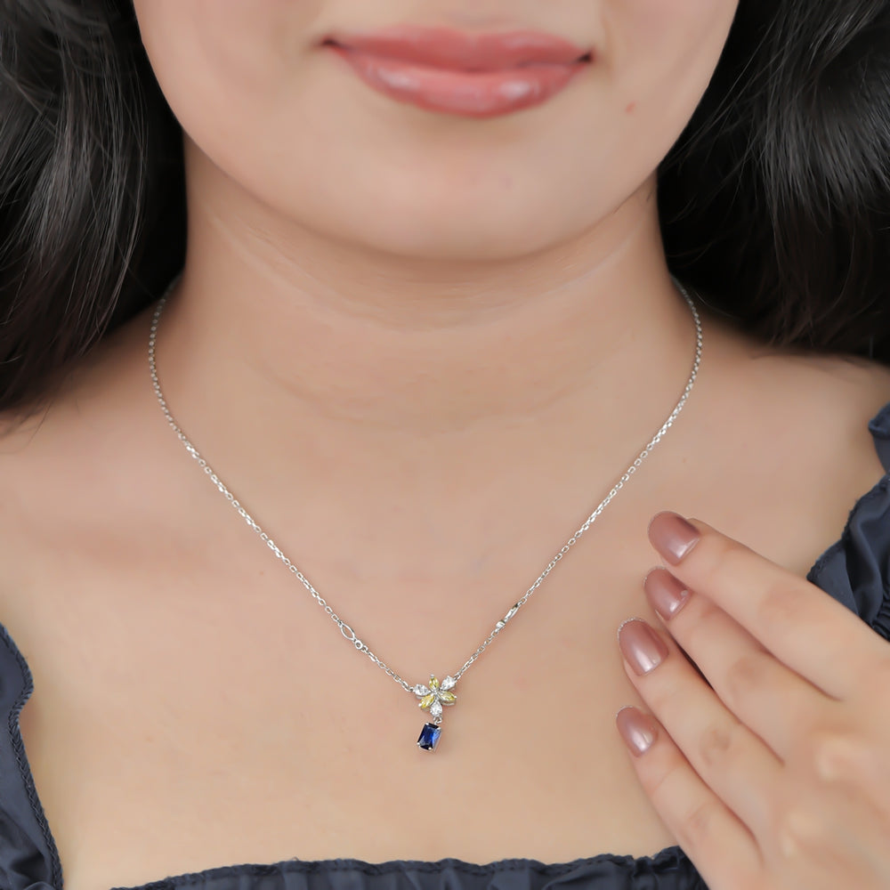 Silver necklace with a yellow floral pendant and blue gem
