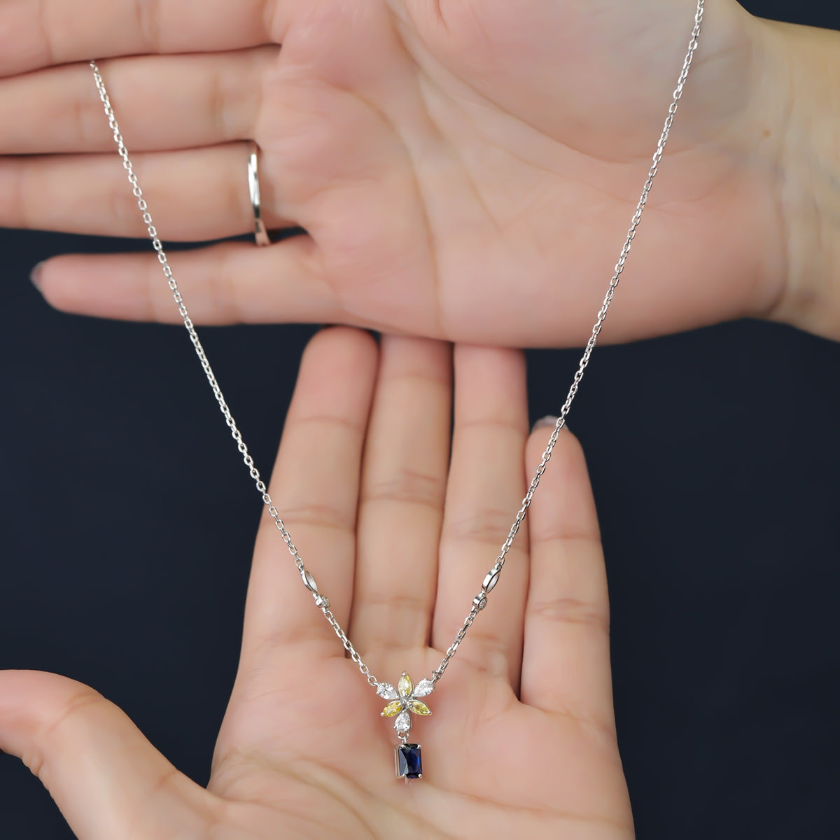 Silver necklace with a yellow floral pendant and blue gem